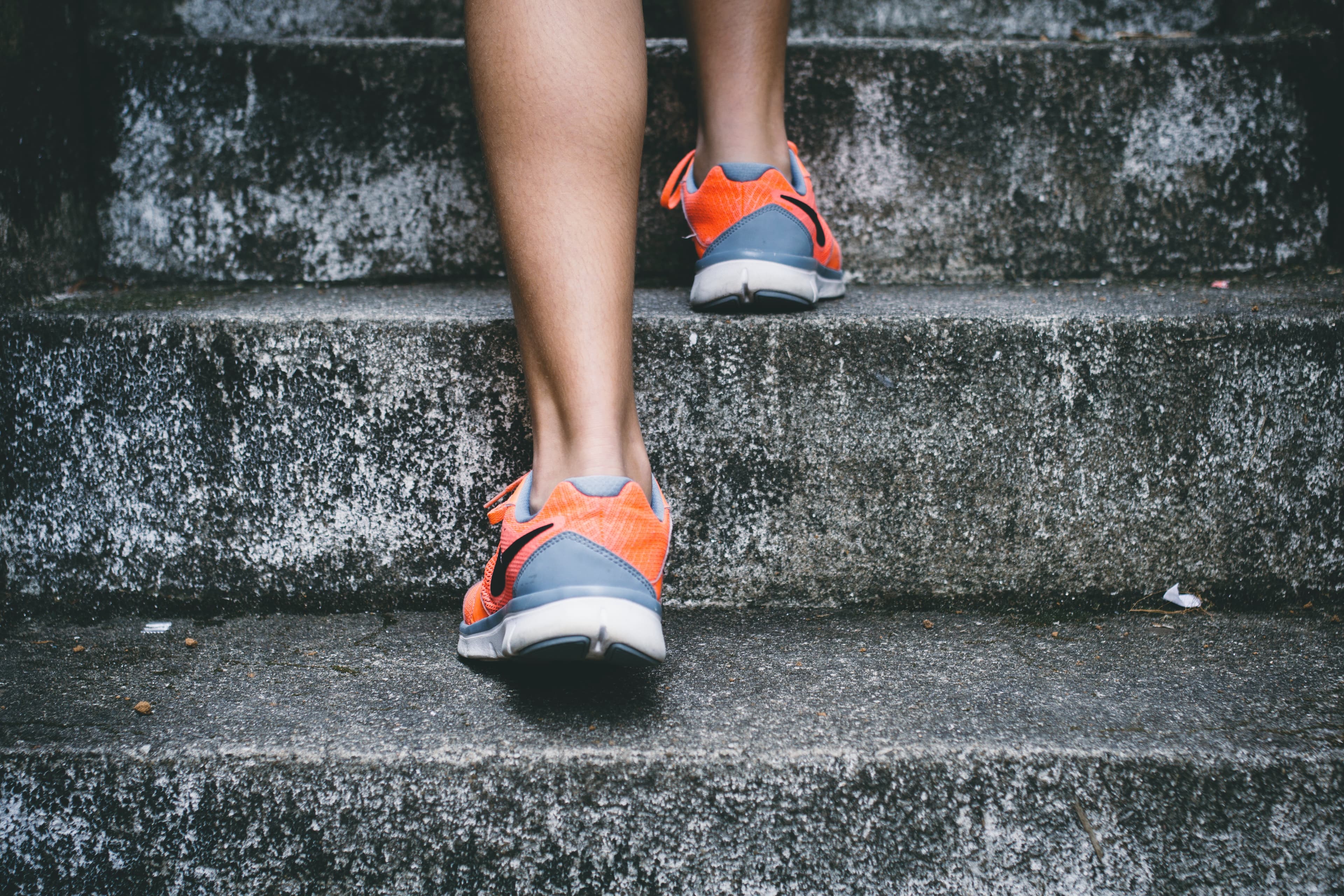 Person wearing orange Nike shoes walking a grey stone staircase outside